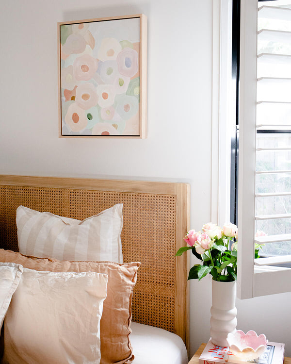 Modern boho bright bedroom styled with earthy decor and a pastel floral Australian artwork