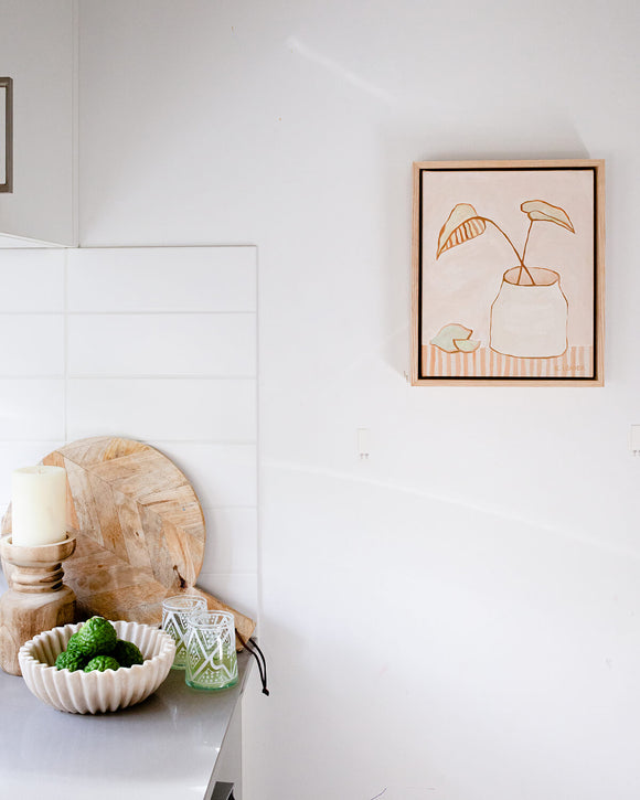 Australian artwork depicting two leaves in a vase in neutral tones, styled with boho decor in a modern kitchen